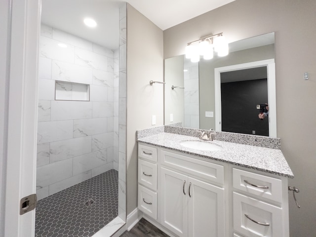 bathroom featuring a tile shower, hardwood / wood-style flooring, and vanity