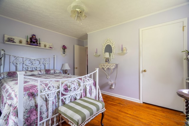 bedroom featuring hardwood / wood-style flooring, crown molding, and a textured ceiling