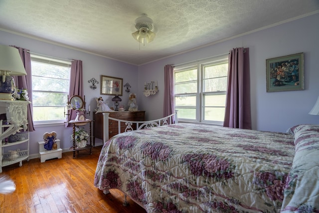 bedroom featuring multiple windows, ornamental molding, light wood-type flooring, and ceiling fan