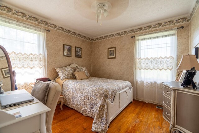 bedroom featuring wood-type flooring, multiple windows, and ceiling fan