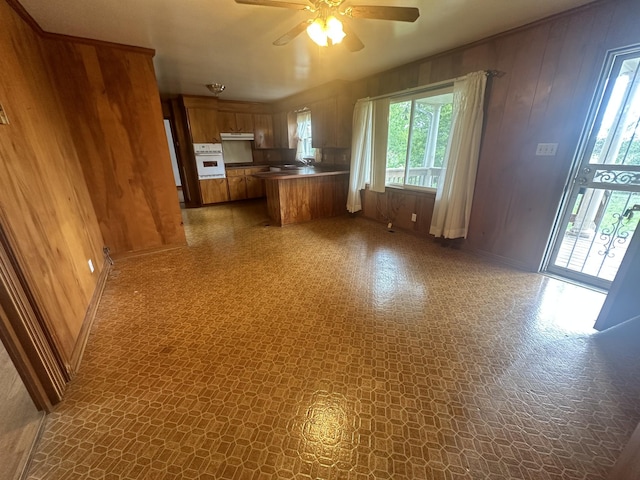 2550 Indian Mound Rd, Woodlawn, TN 37191 - kitchen featuring white oven, wooden walls, brown cabinets, open floor plan, and ceiling fan