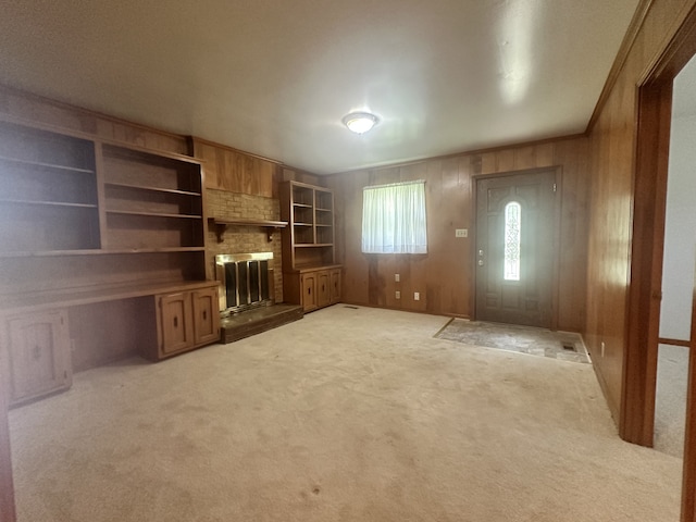 unfurnished living room featuring carpet flooring, wooden walls, and a fireplace