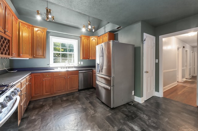 kitchen featuring a textured ceiling, decorative light fixtures, dark wood-type flooring, appliances with stainless steel finishes, and a notable chandelier