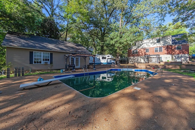 view of swimming pool with a patio area and a diving board