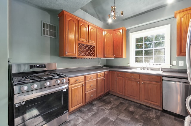 kitchen with a textured ceiling, sink, lofted ceiling, an inviting chandelier, and stainless steel appliances