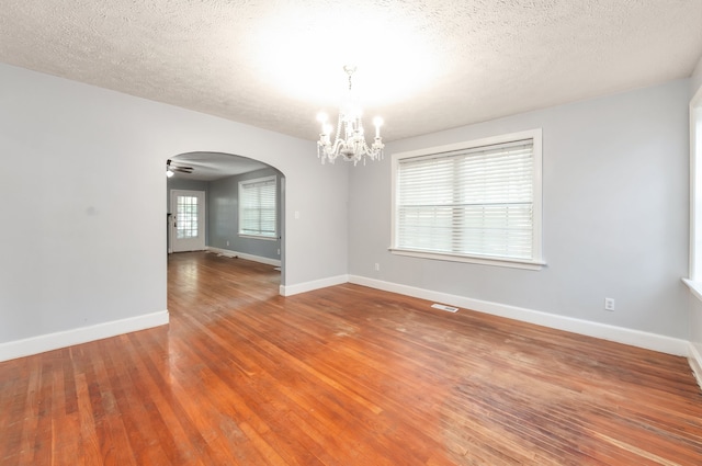 unfurnished room with wood-type flooring, a textured ceiling, and ceiling fan with notable chandelier