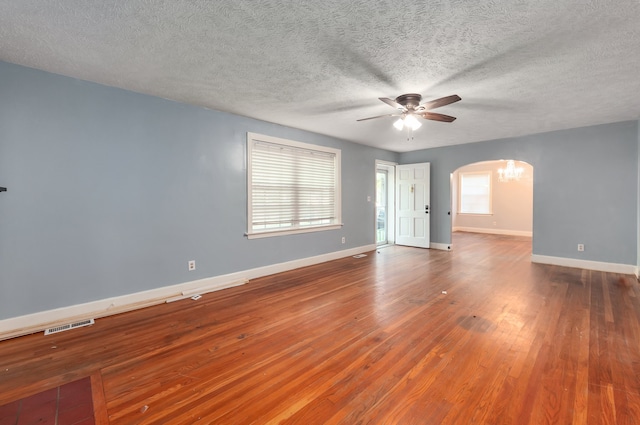 empty room featuring wood-type flooring, a textured ceiling, a wealth of natural light, and ceiling fan