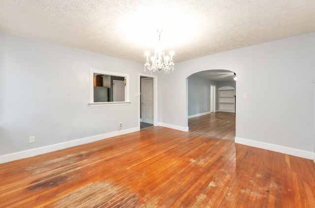 unfurnished room with wood-type flooring, a textured ceiling, and a notable chandelier