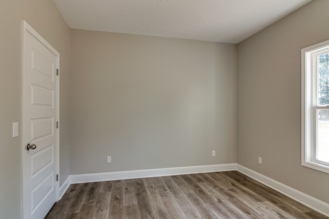 empty room featuring a textured ceiling, a healthy amount of sunlight, and wood-type flooring