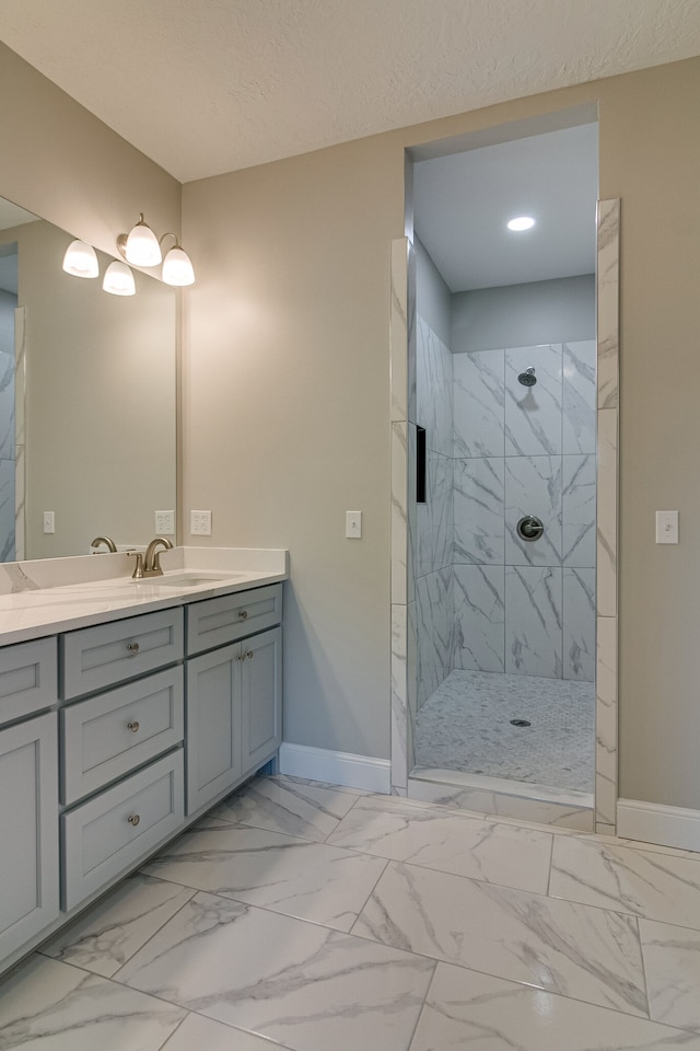 bathroom featuring a textured ceiling, vanity, and tiled shower