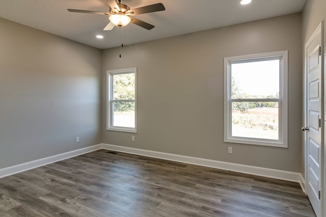 unfurnished room featuring a wealth of natural light, ceiling fan, and dark wood-type flooring