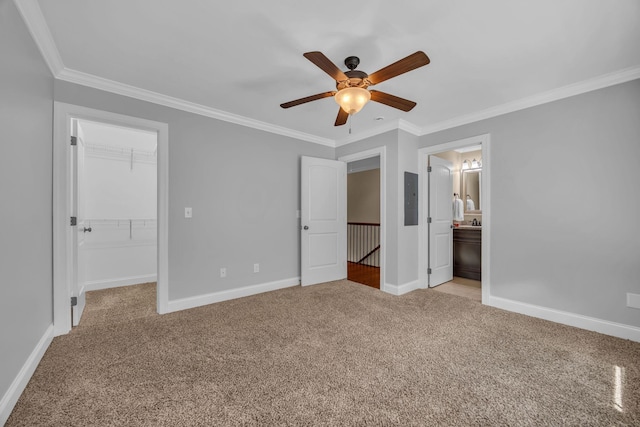 unfurnished bedroom featuring ensuite bathroom, crown molding, ceiling fan, a spacious closet, and a closet