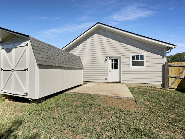 back of house with a lawn, a storage unit, and a patio area