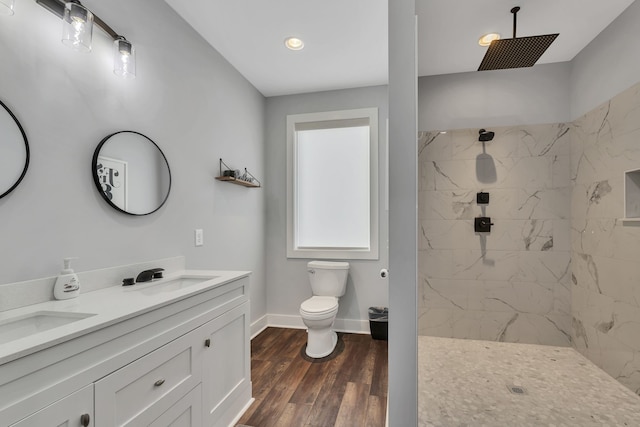 bathroom with hardwood / wood-style floors, tiled shower, vanity, and toilet