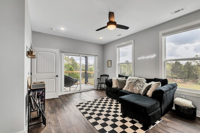 living room with a wealth of natural light, ceiling fan, and dark wood-type flooring