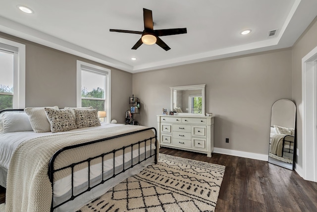 bedroom with ceiling fan, a raised ceiling, and dark hardwood / wood-style floors