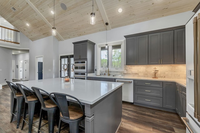 kitchen with a kitchen island, high vaulted ceiling, gray cabinetry, appliances with stainless steel finishes, and decorative light fixtures