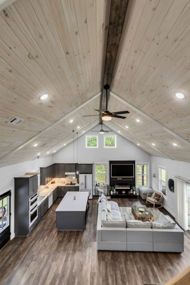 living room featuring ceiling fan, beamed ceiling, dark wood-type flooring, and wooden ceiling