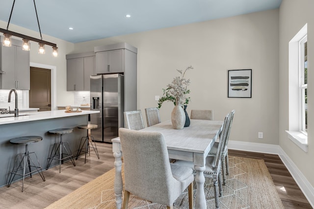 dining space featuring sink, light hardwood / wood-style floors, and plenty of natural light