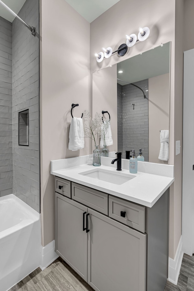 bathroom featuring wood-type flooring, vanity, and tiled shower / bath