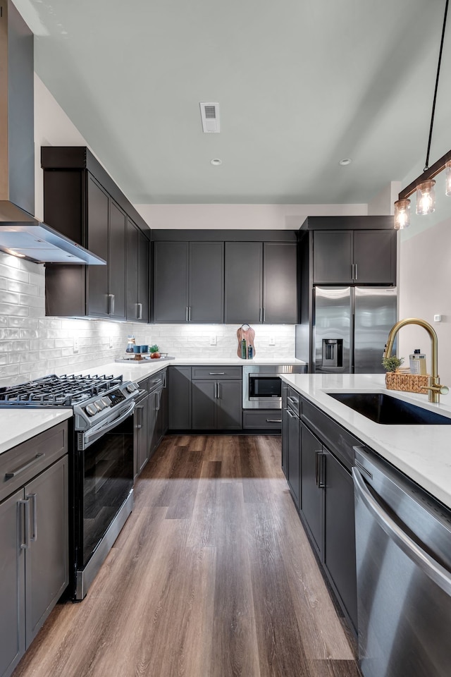 kitchen with appliances with stainless steel finishes, hanging light fixtures, decorative backsplash, dark wood-type flooring, and sink