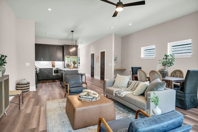 living room with light hardwood / wood-style floors, ceiling fan, and sink