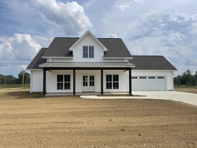 modern farmhouse featuring a garage, covered porch, and a front yard