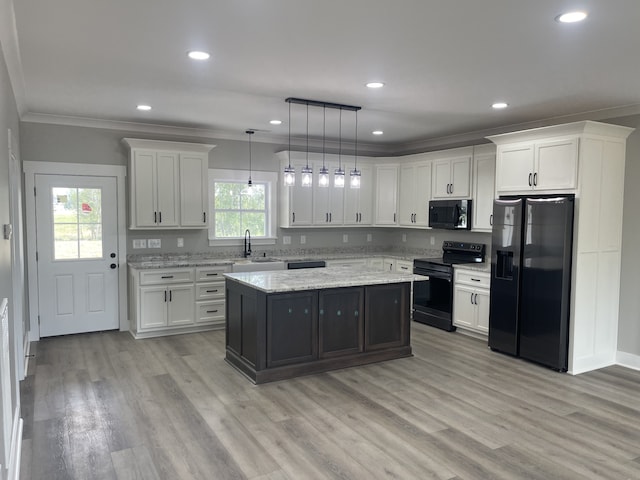 kitchen with hanging light fixtures, white cabinetry, black appliances, a center island, and light hardwood / wood-style floors