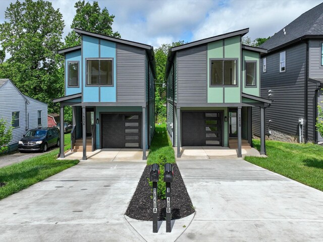 modern home with a garage, concrete driveway, a front lawn, and stucco siding