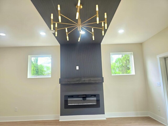 unfurnished living room featuring recessed lighting, wood finished floors, baseboards, and an inviting chandelier