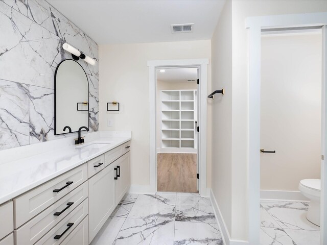 bathroom featuring baseboards, visible vents, marble finish floor, a spacious closet, and vanity