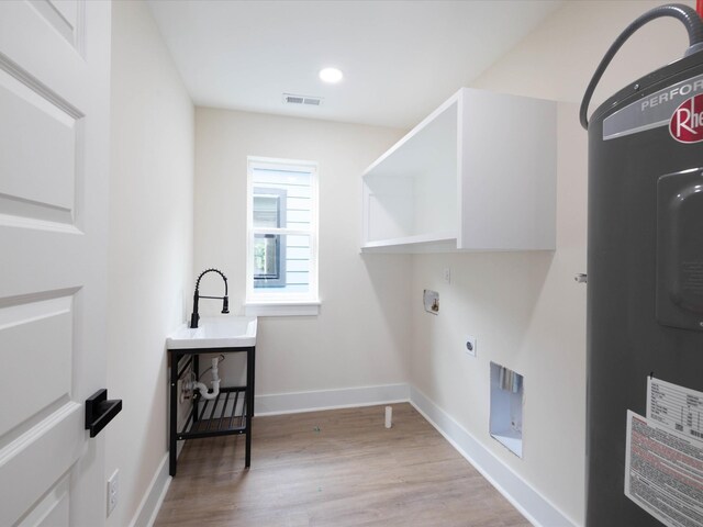 laundry room featuring laundry area, visible vents, baseboards, water heater, and light wood-style floors