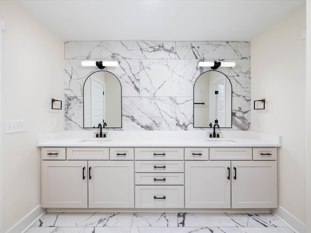 full bath with marble finish floor, a sink, and double vanity