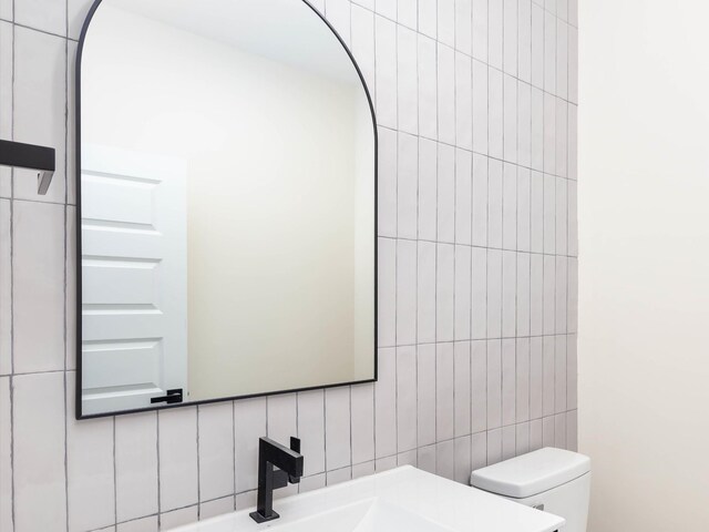 bathroom featuring toilet and tile walls