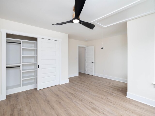 unfurnished bedroom with attic access, light wood-style floors, baseboards, and a ceiling fan