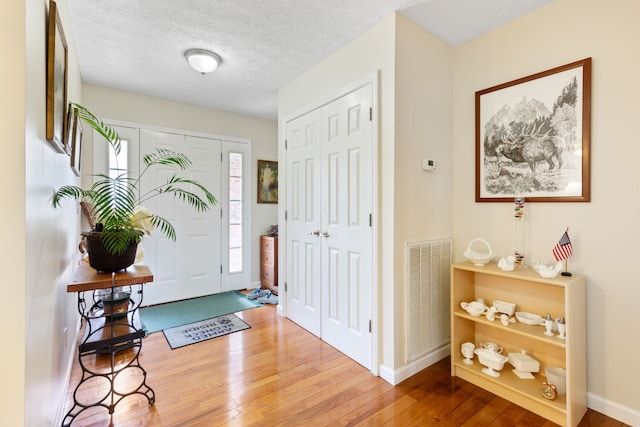 foyer entrance featuring light hardwood / wood-style flooring and a textured ceiling