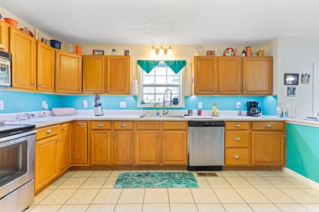 kitchen featuring stainless steel appliances, sink, light tile patterned floors, and a textured ceiling