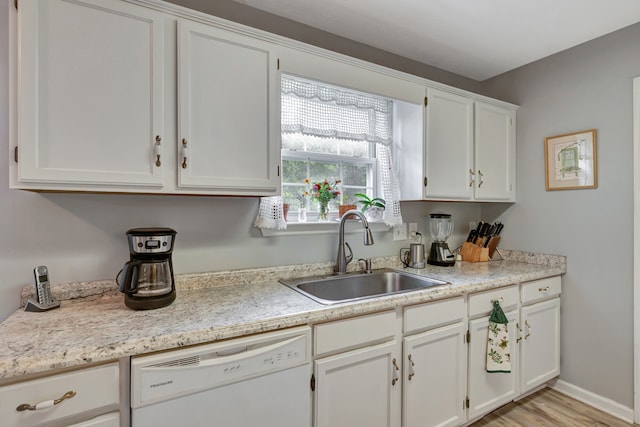 kitchen featuring white dishwasher, white cabinetry, and sink