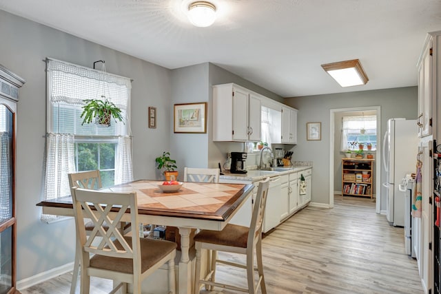 kitchen featuring white cabinetry, white appliances, light wood-type flooring, and sink