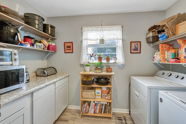 clothes washing area featuring a textured ceiling, light hardwood / wood-style flooring, and washing machine and clothes dryer