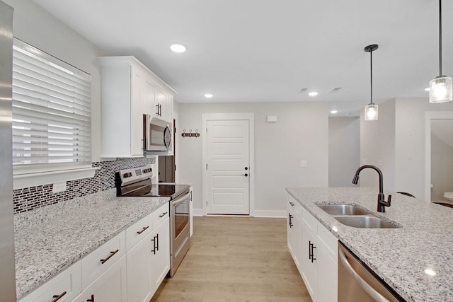 kitchen with pendant lighting, sink, white cabinetry, appliances with stainless steel finishes, and light wood-type flooring