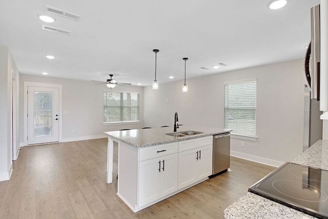 kitchen with light hardwood / wood-style floors, light stone counters, white cabinets, dishwasher, and sink