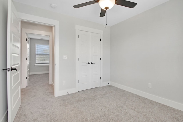 unfurnished bedroom with ceiling fan, a closet, and light carpet