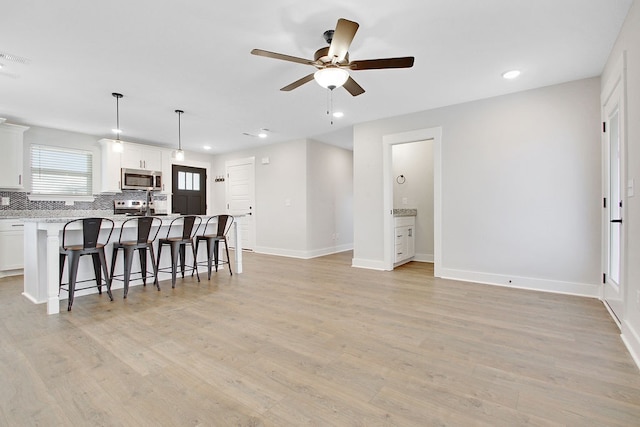 kitchen featuring white cabinets, a kitchen island, light wood-type flooring, ceiling fan, and decorative light fixtures