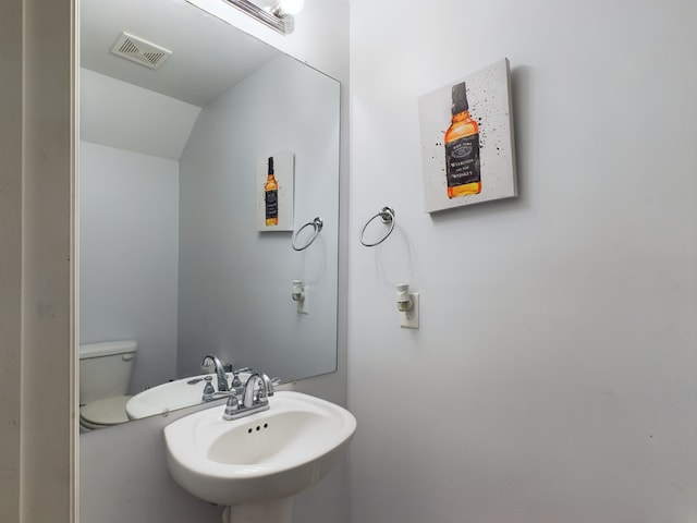 bathroom featuring lofted ceiling, toilet, and sink