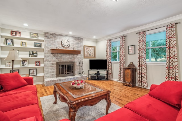 living room featuring a textured ceiling, crown molding, a fireplace, and hardwood / wood-style floors