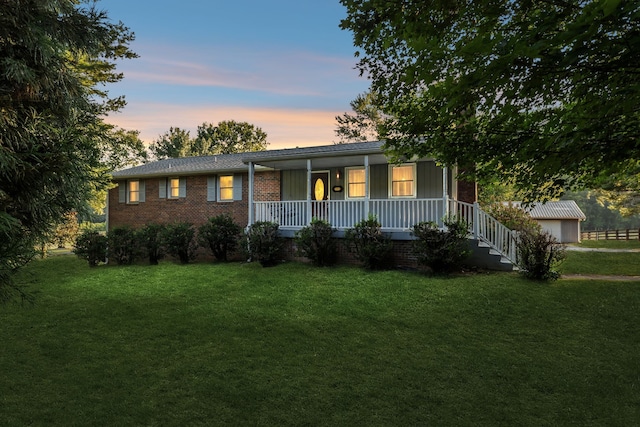 ranch-style home featuring a yard and covered porch