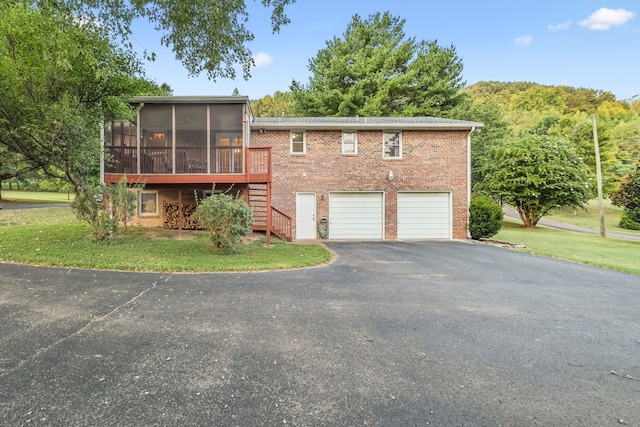 view of front of property with a front yard, a garage, and a sunroom