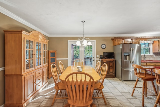 dining area with crown molding, sink, and a chandelier