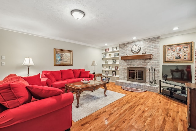 living room with a textured ceiling, a fireplace, crown molding, and hardwood / wood-style floors